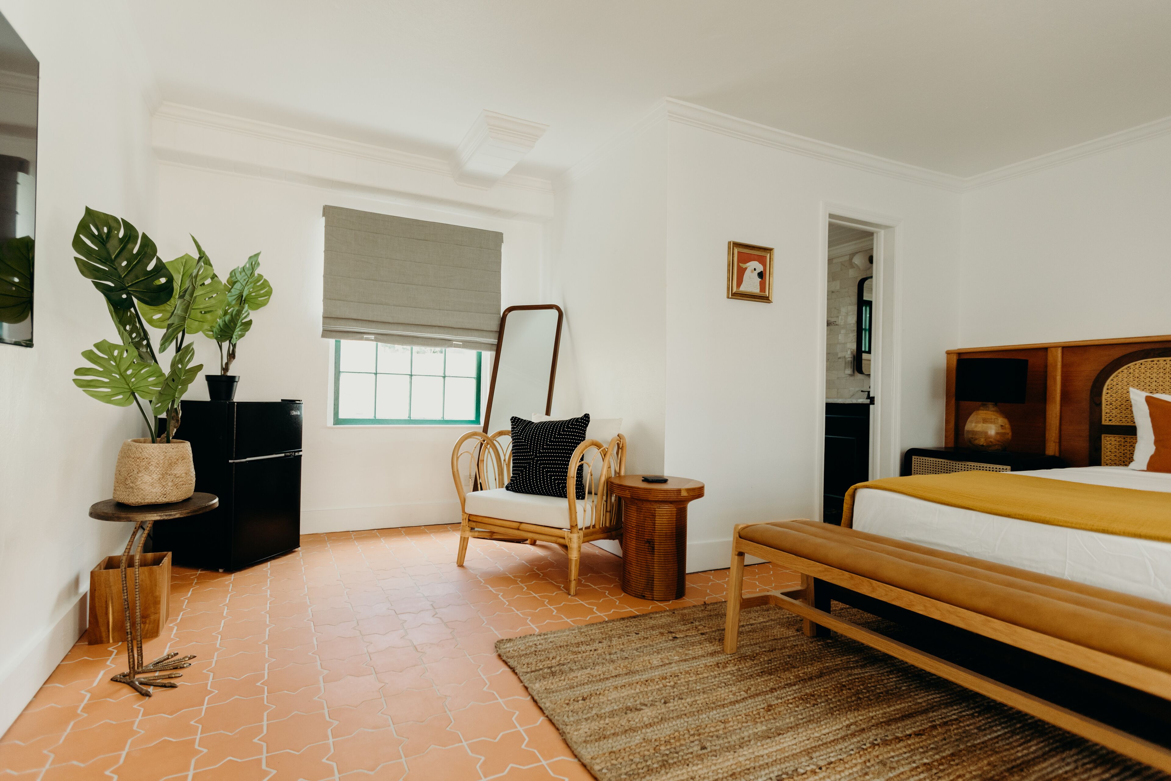 Ein Schlafzimmer mit einem Bett, einem Sessel, einem kleinen Tisch, einer Topfpflanze und einem Fenster mit Aussicht.