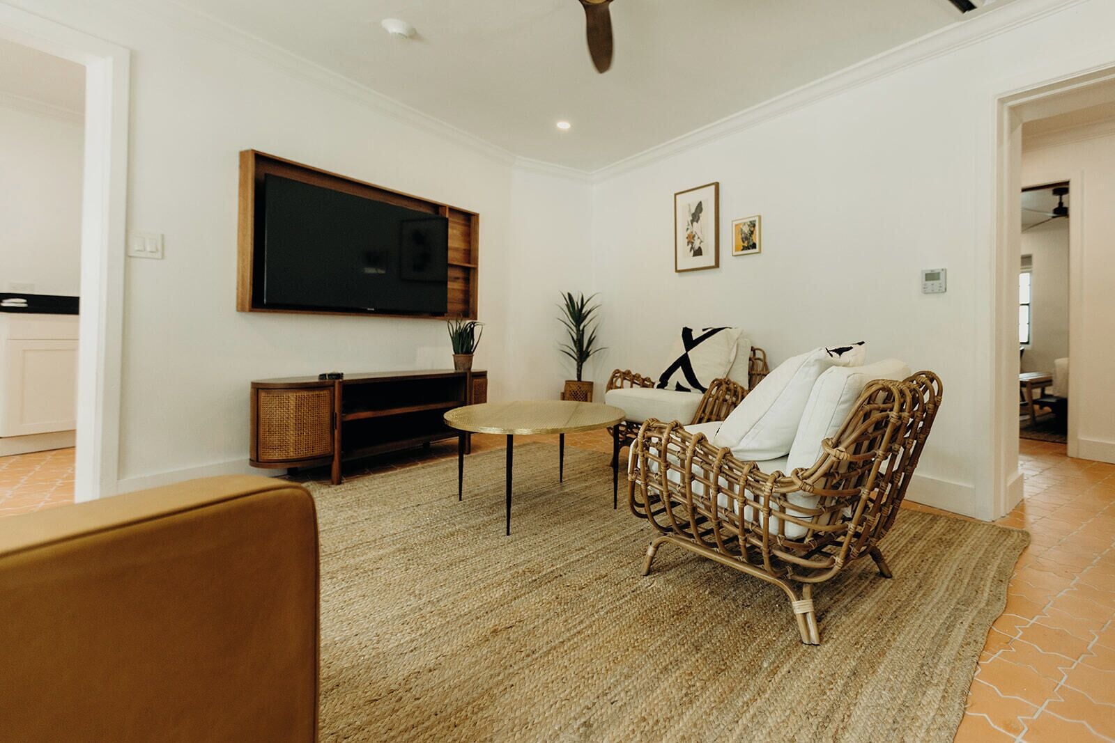 A living room with a television, wicker furniture, a round coffee table, and a rug.