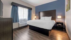 A hotel room with a large bed, a flat-screen TV, a desk with a lamp, and a window with curtains. - Best Western Louisville Airport Expo (Louisville)