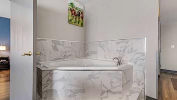 A modern bathroom with a freestanding bathtub, marble tiles, and a painting on the wall.