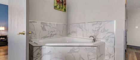 Ein modernes Badezimmer mit freistehender Badewanne, Marmorfliesen und einem Bild an der Wand.