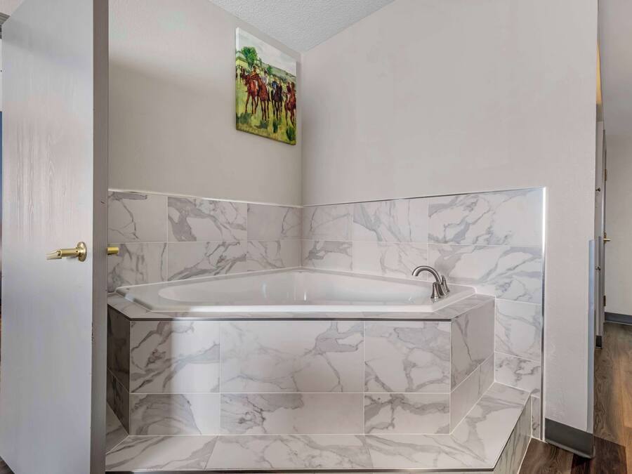 Un baño moderno con una bañera independiente, baldosas de mármol y un cuadro en la pared.
