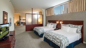 A hotel room with two beds, a TV, a desk, and a view of the city. - Le Square Phillips Hotel And Suites (Montreal)