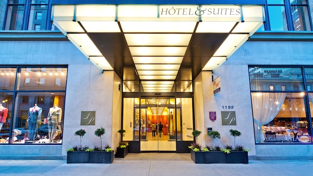 The exterior of a hotel with a prominent entrance, large glass windows, and a sign indicating it is a hotel and suites. - Le Square Phillips Hotel And Suites (Montreal)