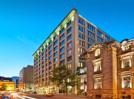 A multi-story hotel with a classic architectural design, featuring a prominent entrance with a green awning and a large window display.