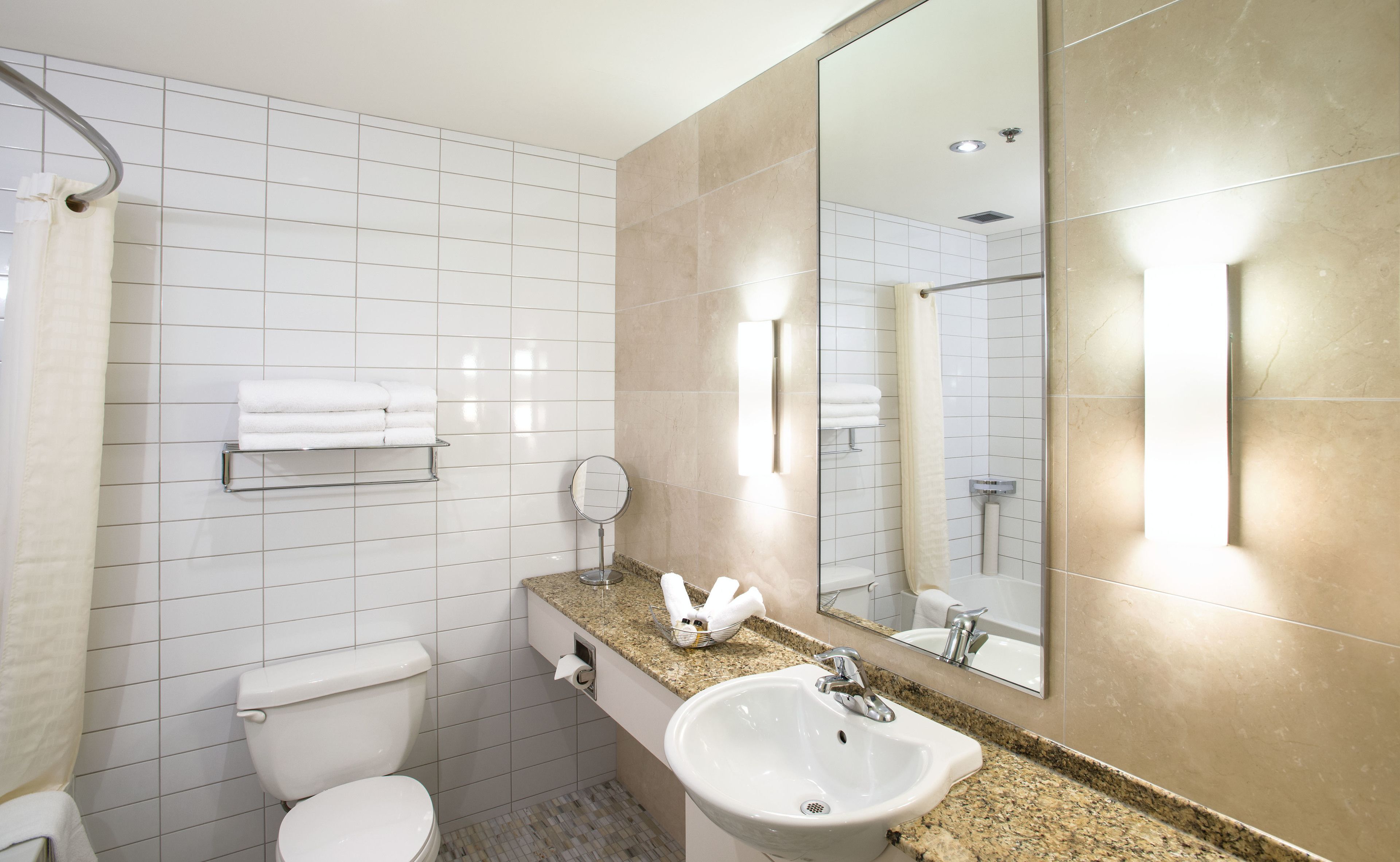 Un baño moderno con inodoro, lavamanos y un espejo grande.