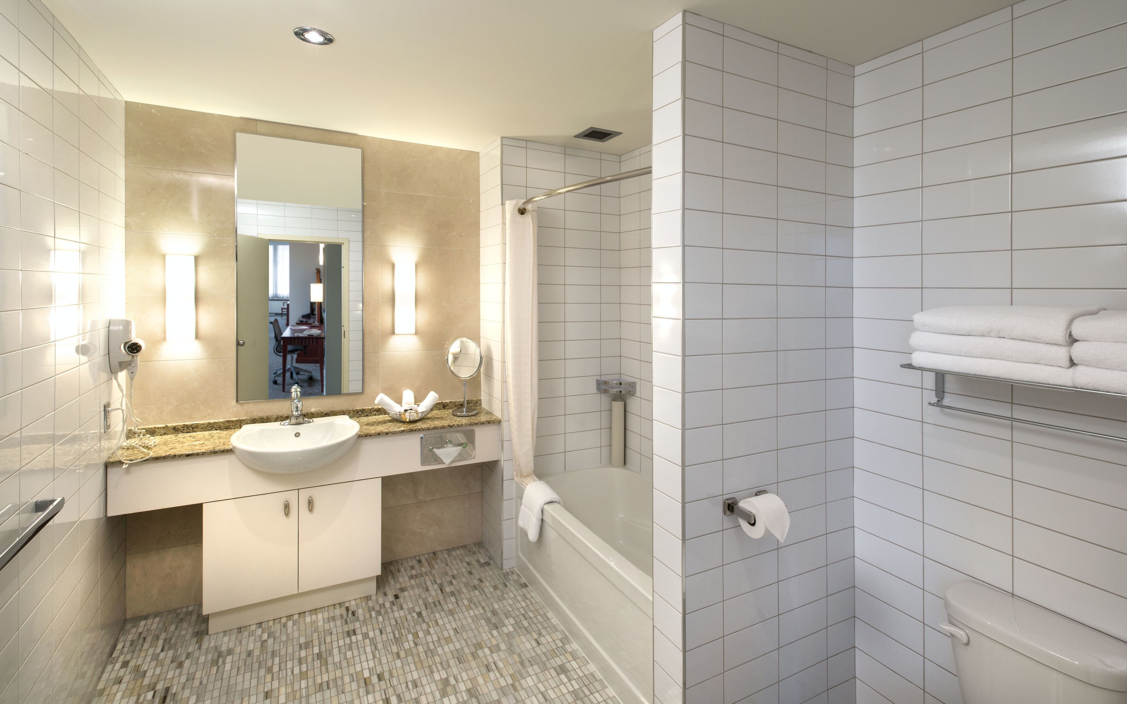 A modern bathroom with a sink, mirror, and shower.