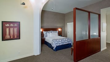 A bedroom with a bed, a nightstand, a wooden wardrobe, and a framed picture on the wall.