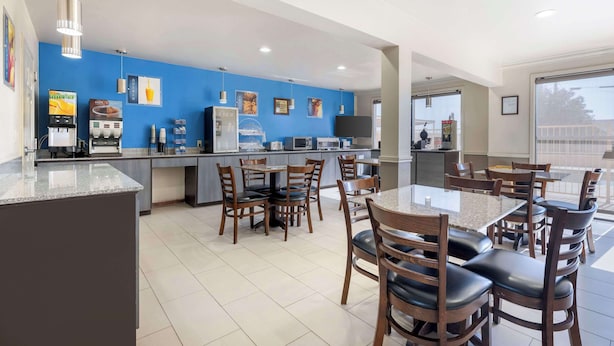 A modern dining area with a blue wall, a coffee machine, and several tables and chairs.