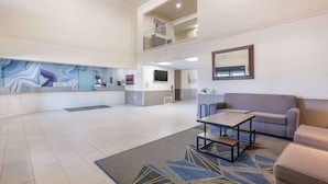 A spacious lobby with a marble wall, a reception desk, a sofa, and a coffee table.