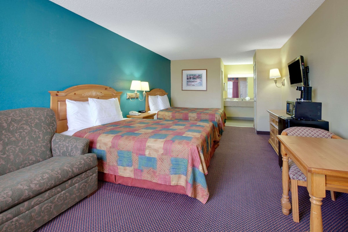 A hotel room with a bed, a sofa, a desk, and a television.