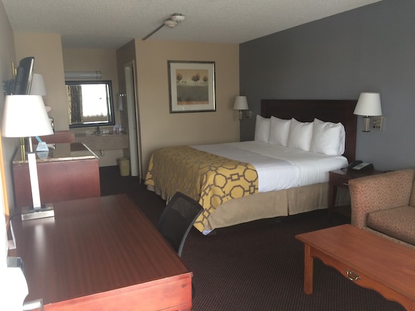 Una habitación de hotel con cama, escritorio, silla y una mesita.