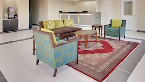 Un espacio moderno con sala, sofá, sillones, cafetera y televisor.