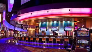 Un bar de casino doté de plusieurs écrans, de machines à sous et d’un comptoir incurvé.
