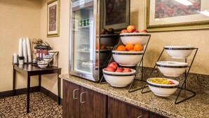 Un espace où est servi le petit-déjeuner à l’hôtel, équipé d’un réfrigérateur, de corbeilles de fruits et d’un coin café.