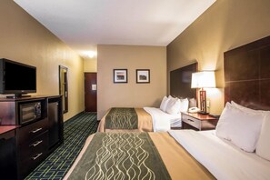 A hotel room with a bed, a desk with a lamp, a TV, and a minibar.