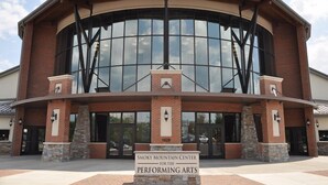 Un bâtiment doté d’une grande façade en verre, d’une façade extérieure en briques et d’une enseigne indiquant qu’il s’agit du « Smoky Mountain Center for the Performing Arts ».