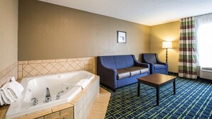 Une chambre d’hôtel avec une grande baignoire, un canapé, un fauteuil et une petite table.
