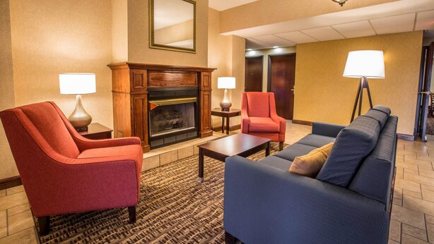 Un hall d’hôtel avec une cheminée, deux fauteuils, un canapé et une table basse.
