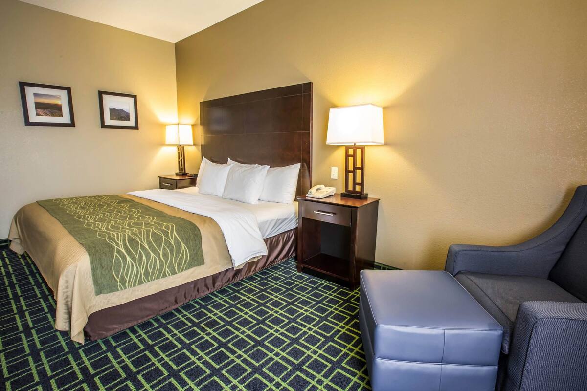 A hotel room with a bed, two bedside lamps, a telephone, a small table, and a sofa.