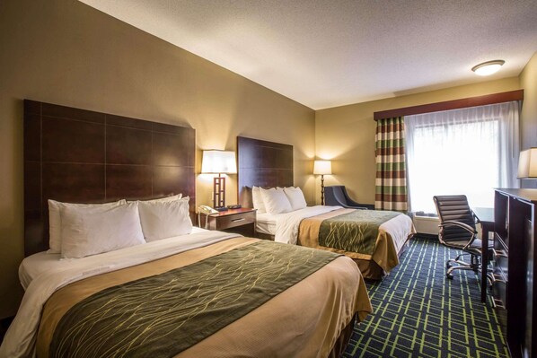 A hotel room with two beds, a desk, a chair, and a window with curtains.