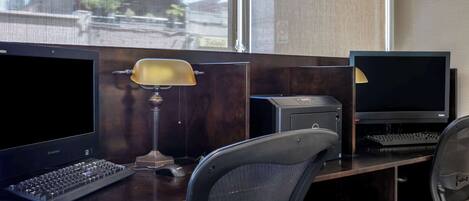 A workspace with two monitors, a keyboard, a lamp, and a chair.