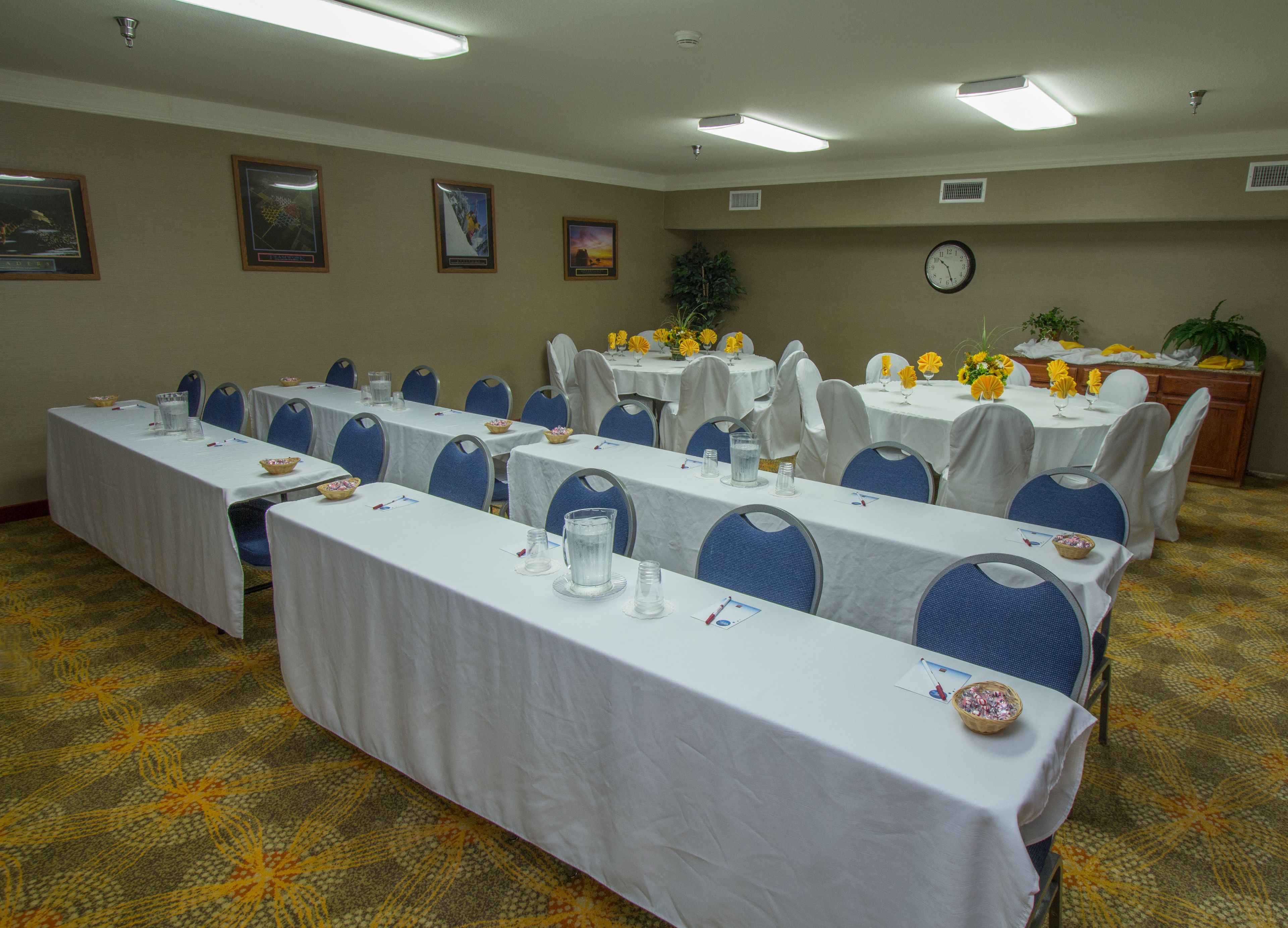 Un salón de conferencias con varias mesas, sillas y un reloj en la pared.