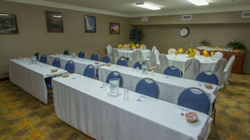 Uma sala de conferências com várias mesas, cadeiras e um relógio na parede.