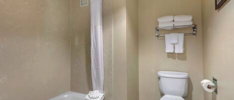 A bathroom with a bathtub, toilet, and a towel rack with folded towels.