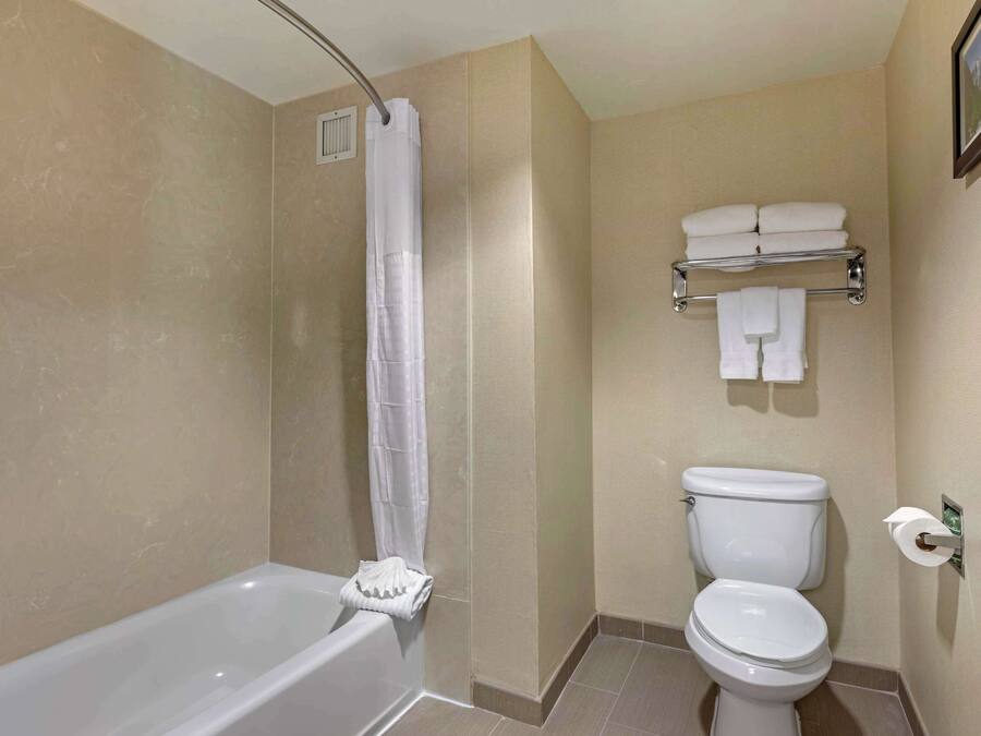 Un baño con bañera, inodoro y toallero con toallas dobladas.