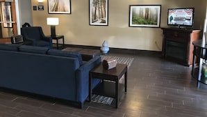 A living room with a sectional sofa, a coffee table, and a fireplace. There are framed pictures on the wall and a television on a stand.