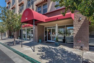 A hotel entrance with a red awning, numbered 210, and a glass door.