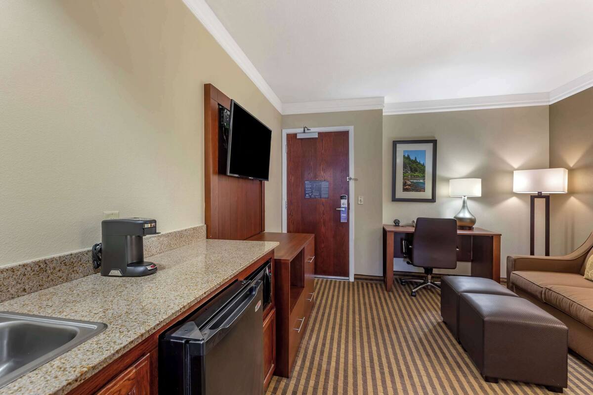 Ein Hotelzimmer mit Küchenzeile, einem Essbereich, einem Sofa und einem Fernseher.