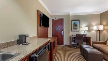 Habitación de hotel con kitchenette, zona de comedor, sofá y televisión.