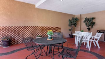 A patio area with a round table and chairs, potted plants, and a lattice wall.