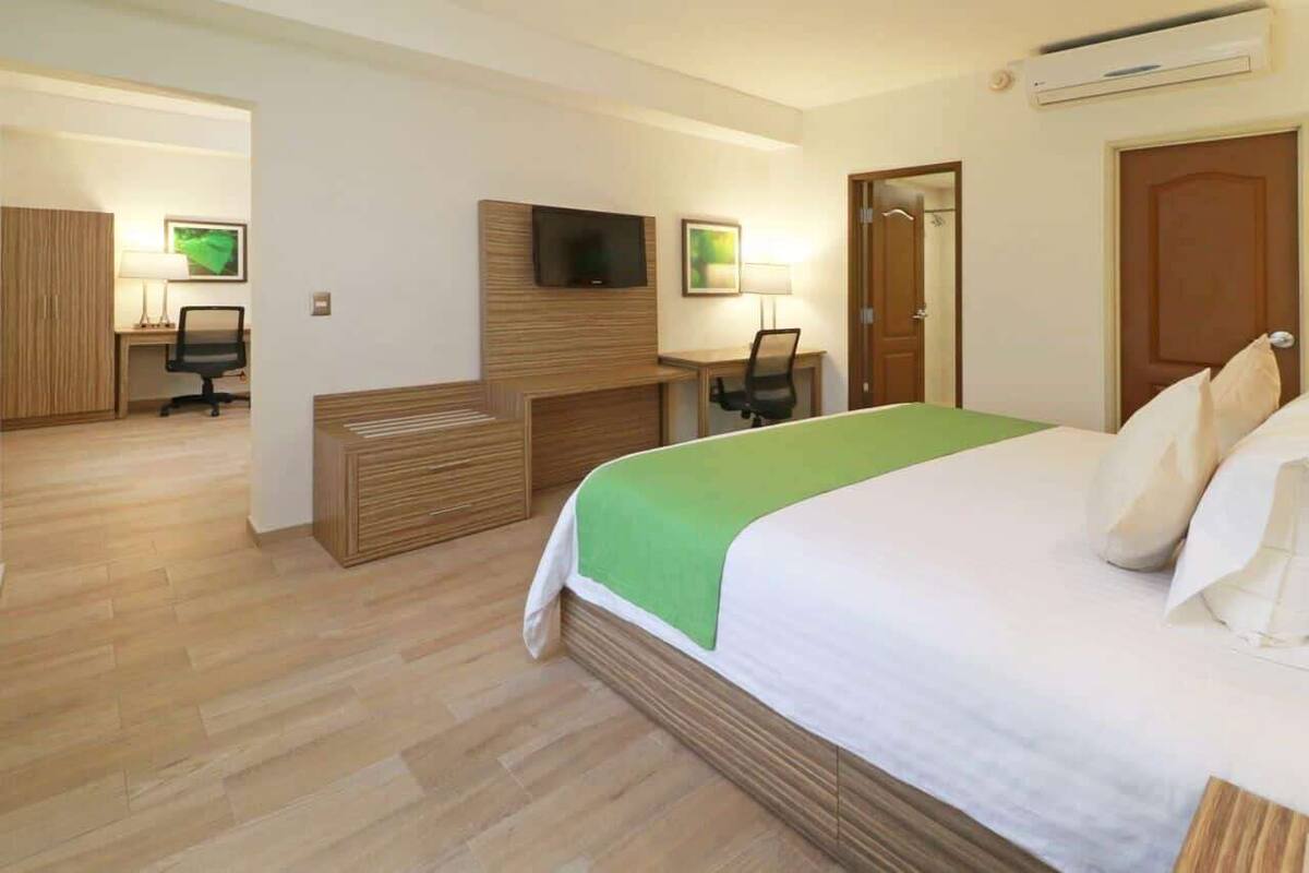 Ein Hotelzimmer mit einem Bett, einem Schreibtisch, einem Stuhl, einem Fernseher und einem Kleiderschrank.