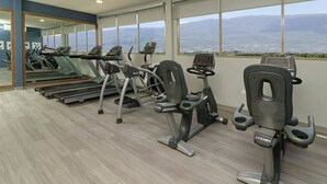 A gym with treadmills, elliptical machines, and stationary bikes, featuring large windows with a city view. - Wyndham Garden Monterrey Valle Real (Monterrey)