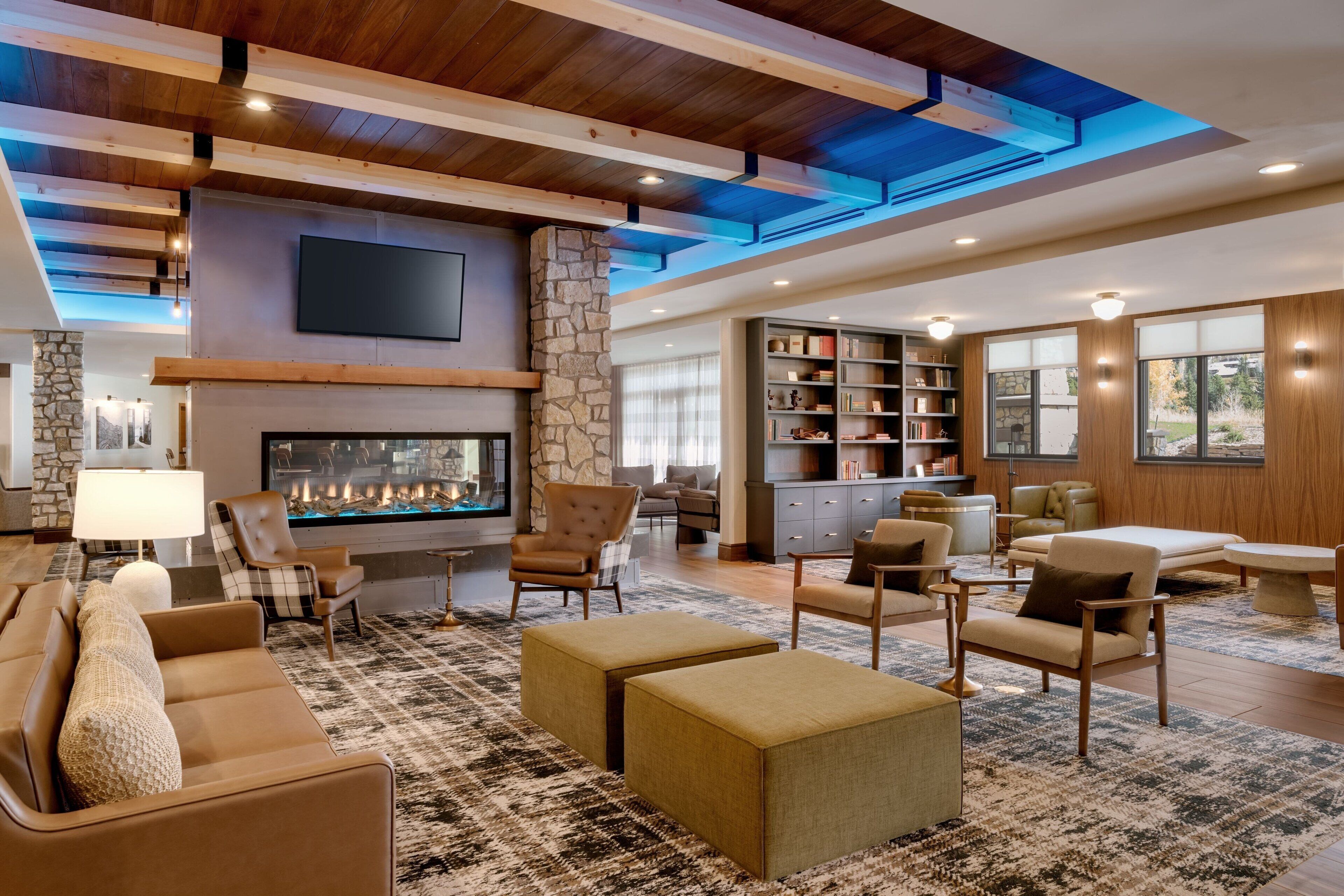 A spacious living area with a stone fireplace, comfortable seating, and a large bookshelf.