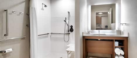 Egy modern fürőszoba zuhanyzóval, mosdókagylóval és tükörrel, valamint WC-vel.