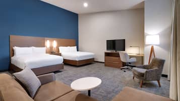 Habitación de hotel con dos camas, un sofá, un escritorio, una silla y un televisor.