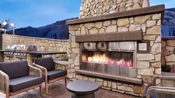 Un patio al aire libre con paredes de piedra, una chimenea integrada y mobiliario exterior.