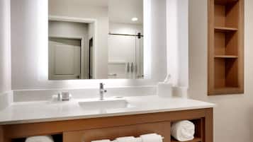 A modern bathroom with a white sink, mirror, and wooden vanity.