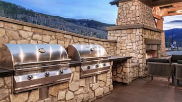 Cocina al aire libre de piedra con una parrilla y chimenea de piedra, con vistas a un paisaje montañoso.