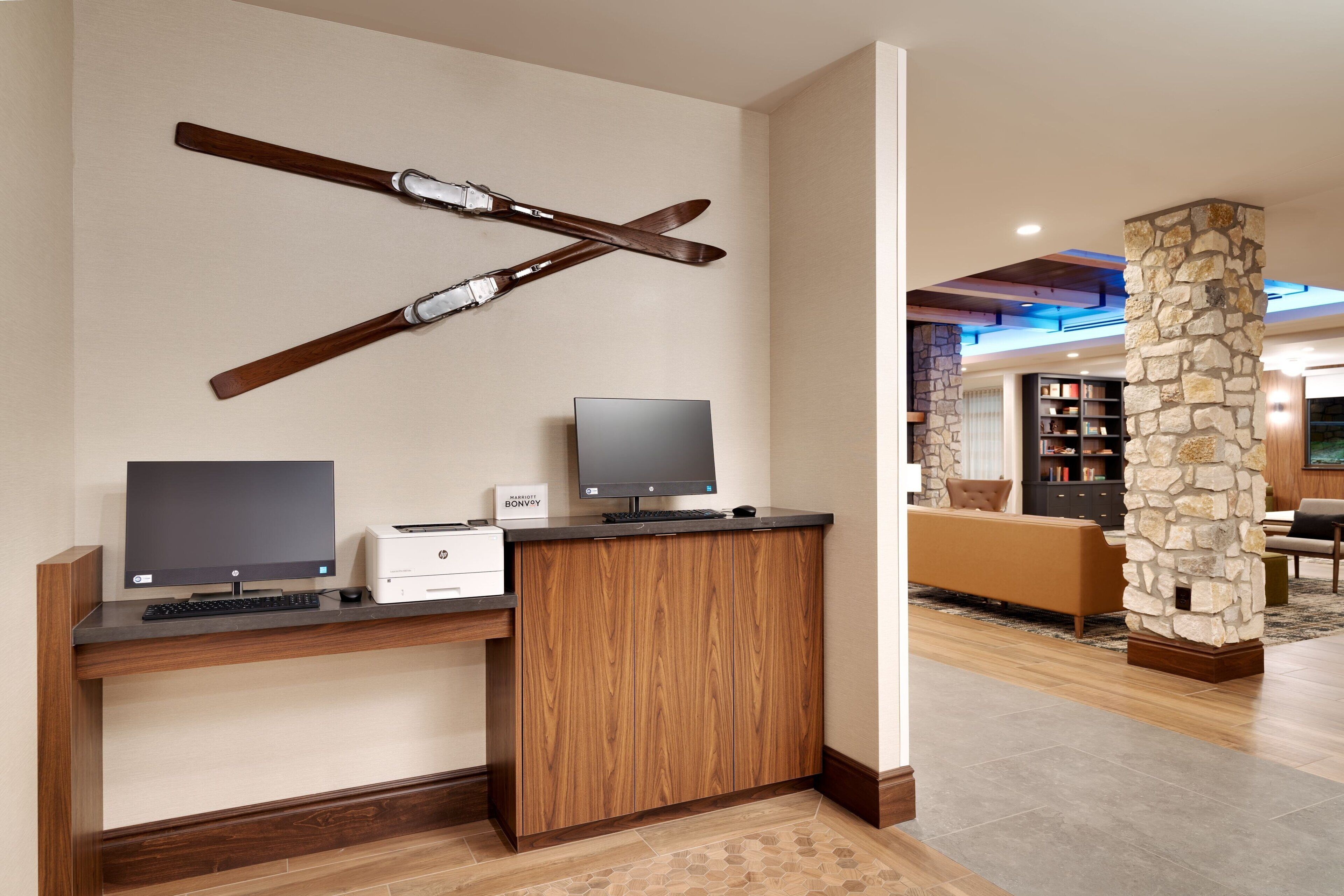 A modern living room with a wooden entertainment center, a flat-screen TV, and a stone pillar.