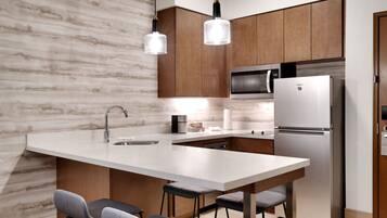 A modern kitchen with a marble backsplash, wooden cabinets, stainless steel appliances, and pendant lighting.