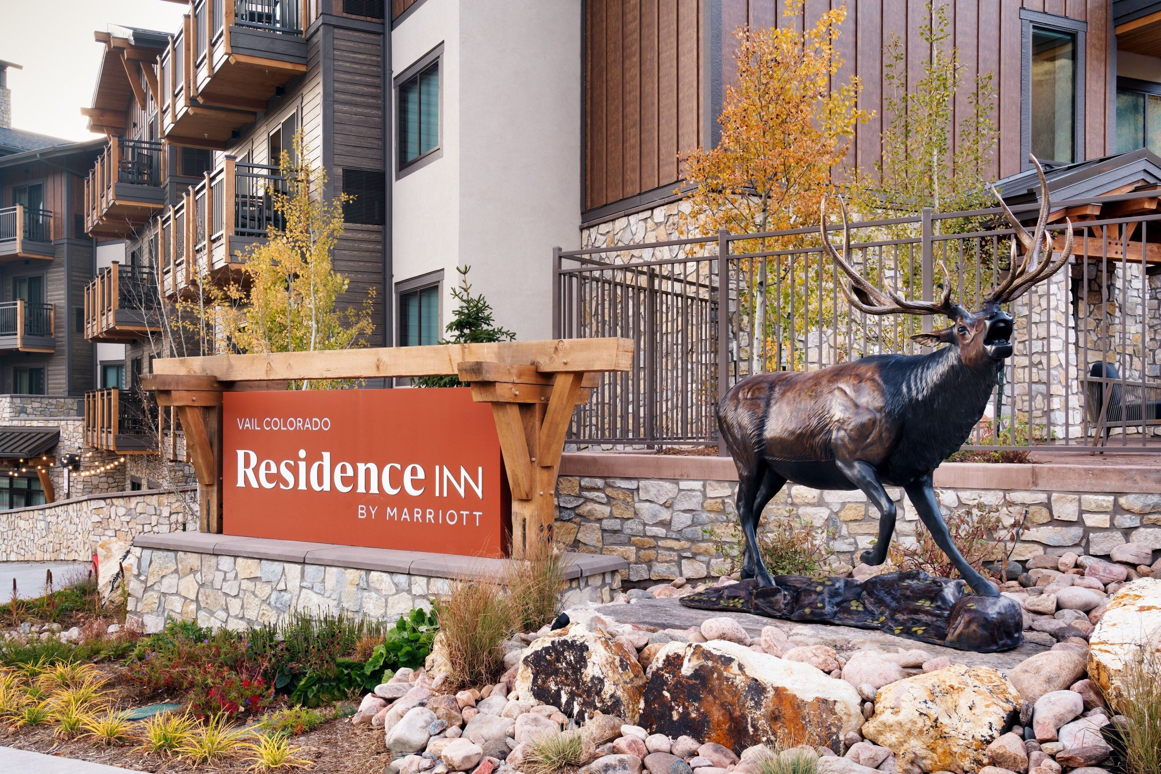Schild für das Vail Colorado Residence Inn by Marriott, mit einer Hirschstatue und einer Steinmauer mit Pflanzen.
