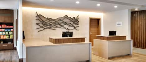 Ett välkomnande område med modern design, med en reception i trä, ett abstrakt konstverk på väggen och en skylt som visar namnet ”BONVYSY”.