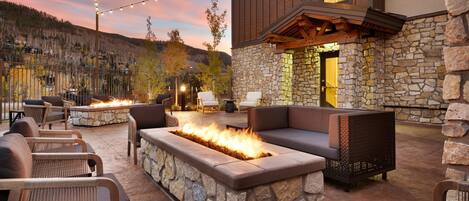 An outdoor patio with stone walls, a fire feature, and string lights.