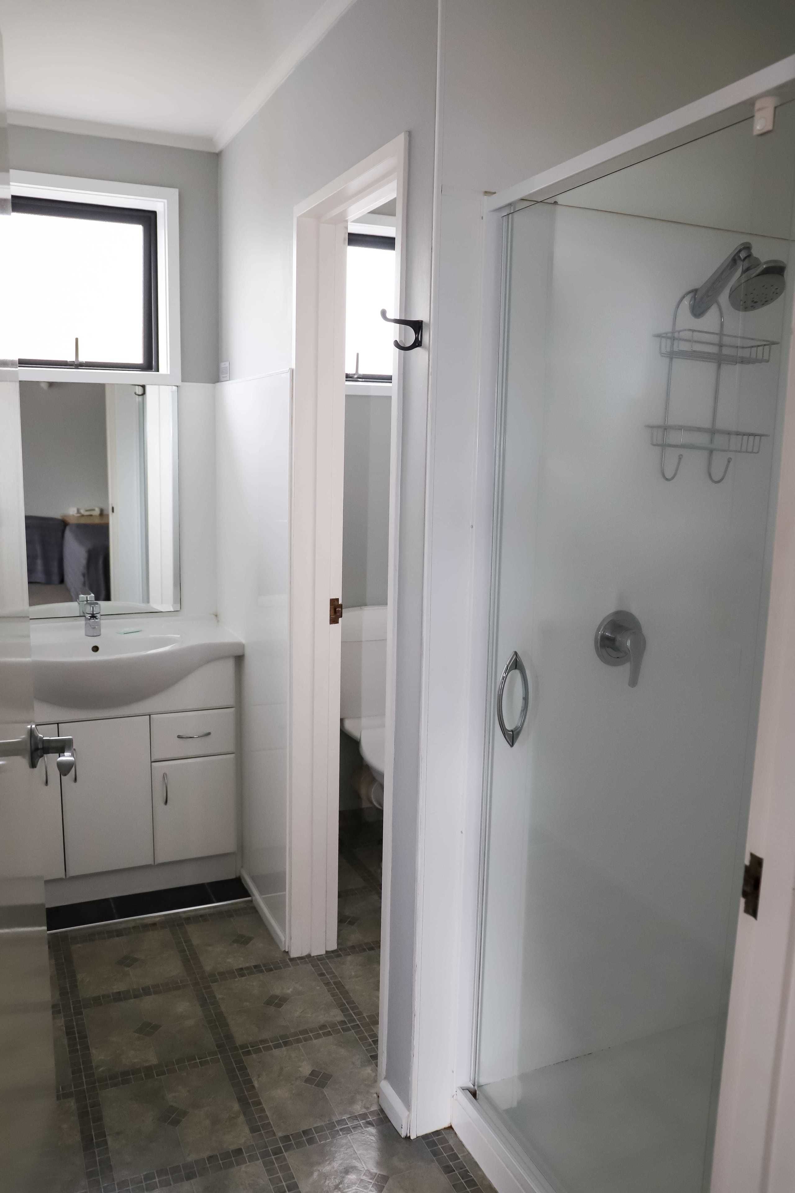 A bathroom with a white sink, mirror, and shower area.