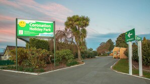 A sign for Coronation Holiday Park with amenities listed, including a swimming pool and self-contained units. - Coronation Park (Ashburton)